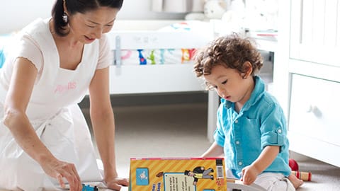 A nanny reading with a child in a nursery