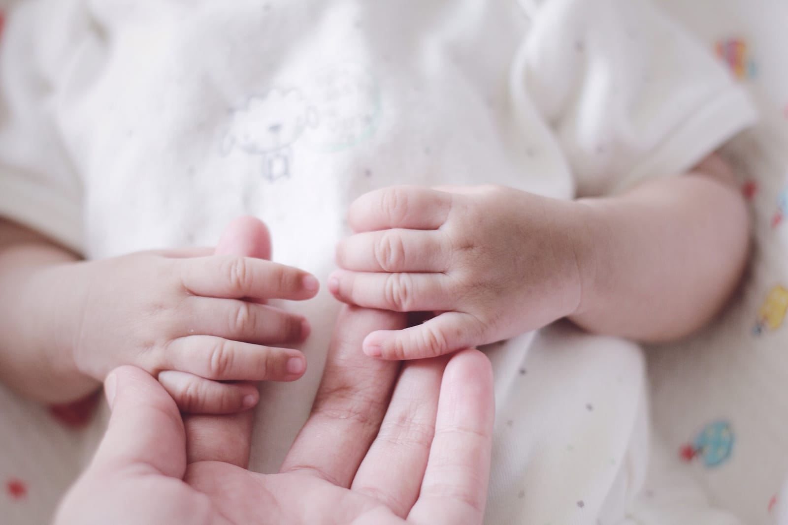 A newborn holding a caregiver's hand