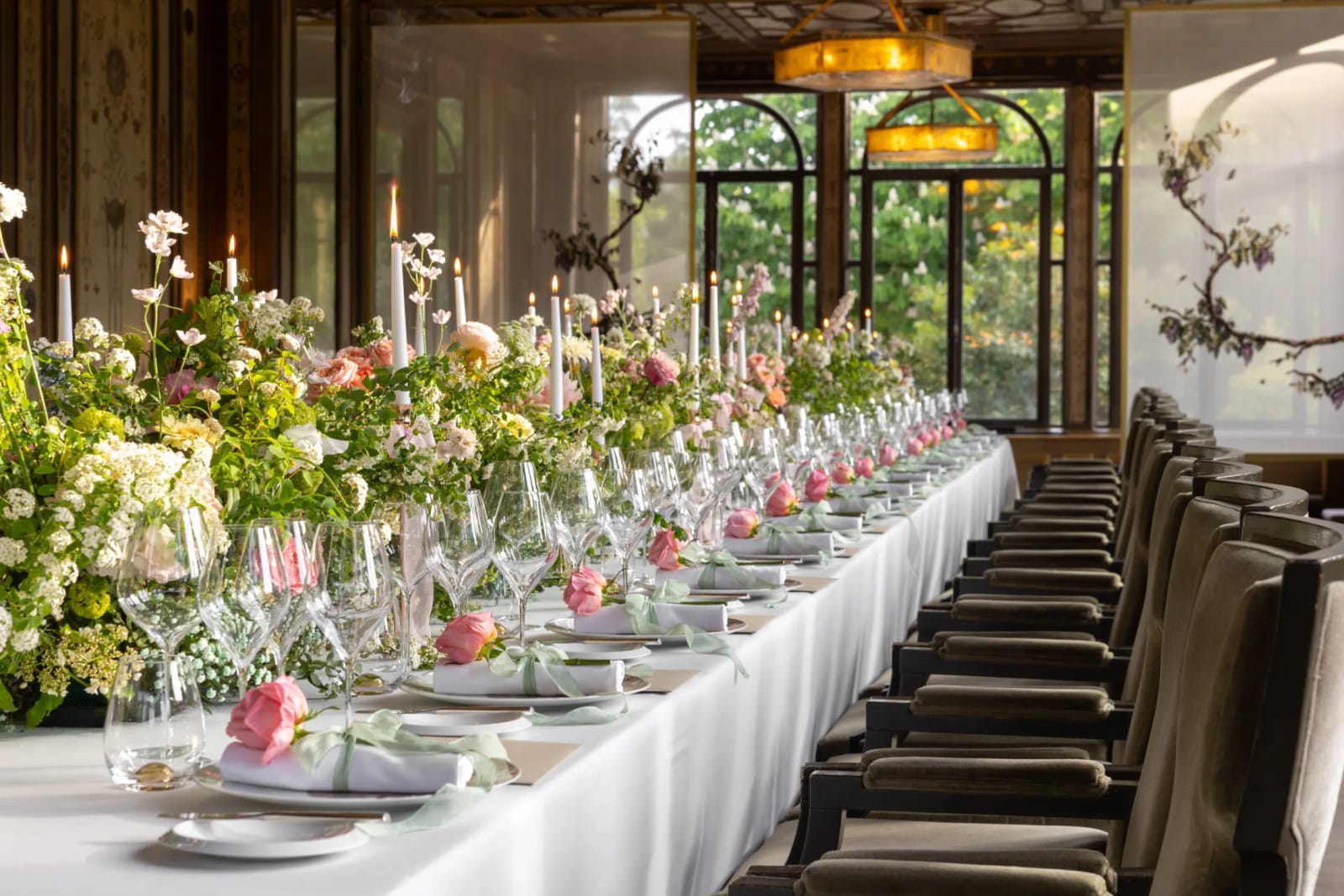 A long table laid in the room, trees beyond the windows
