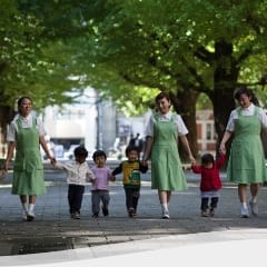 Nannies walking children under ginkgo trees