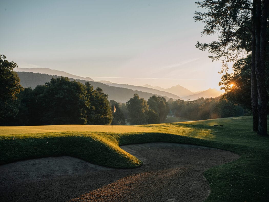 A green at sunrise, the Pre-Alps behind