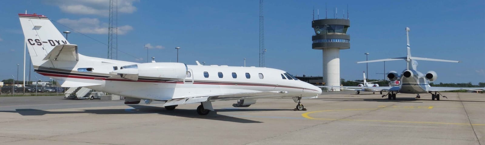 Private jets parked on the apron by the tower