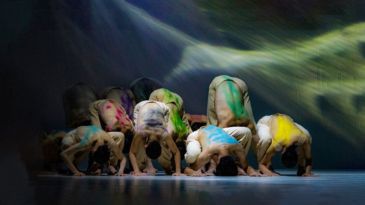 Dancers bowed to the floor, their backs marked with colour