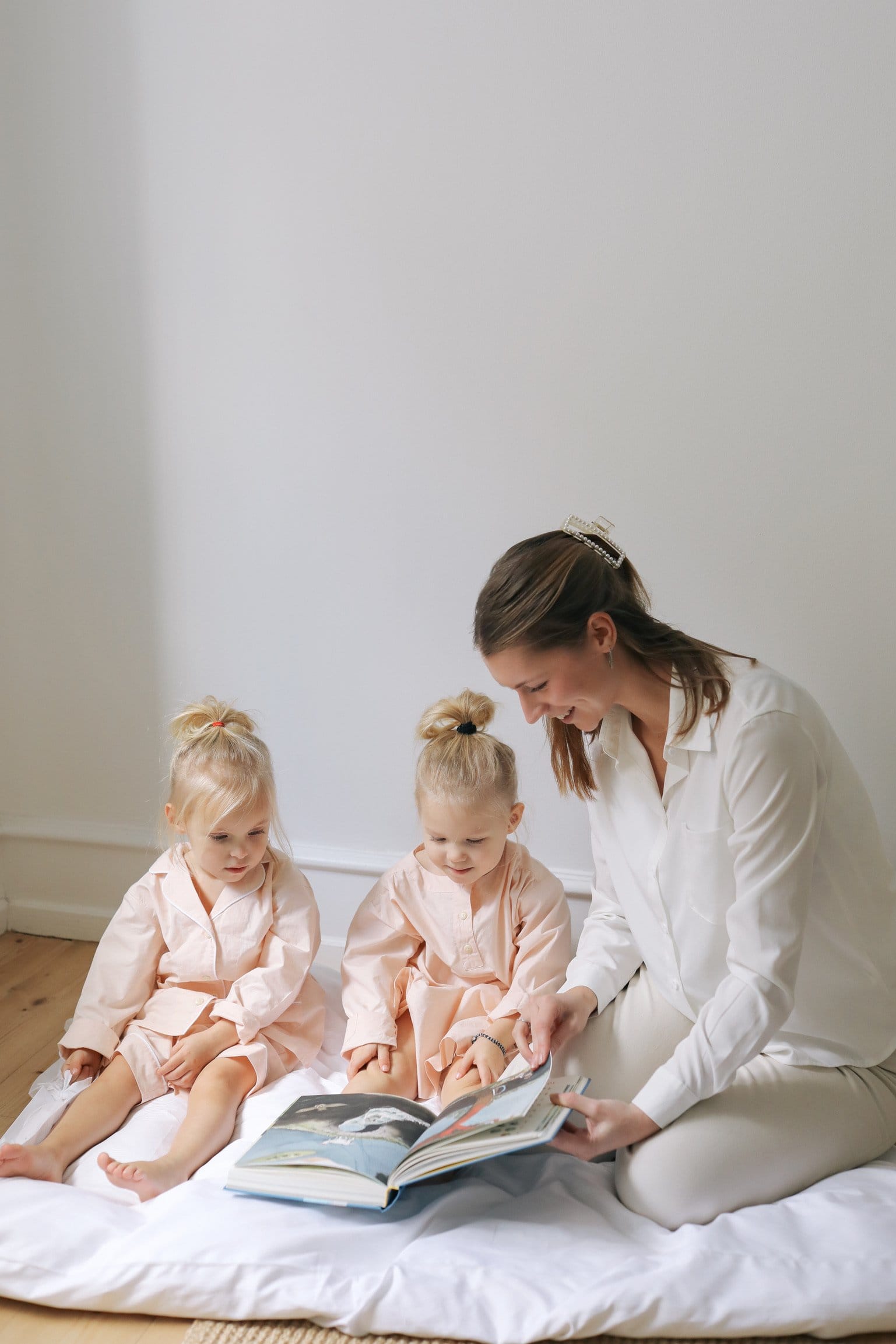 A nanny reading a picture book with two children