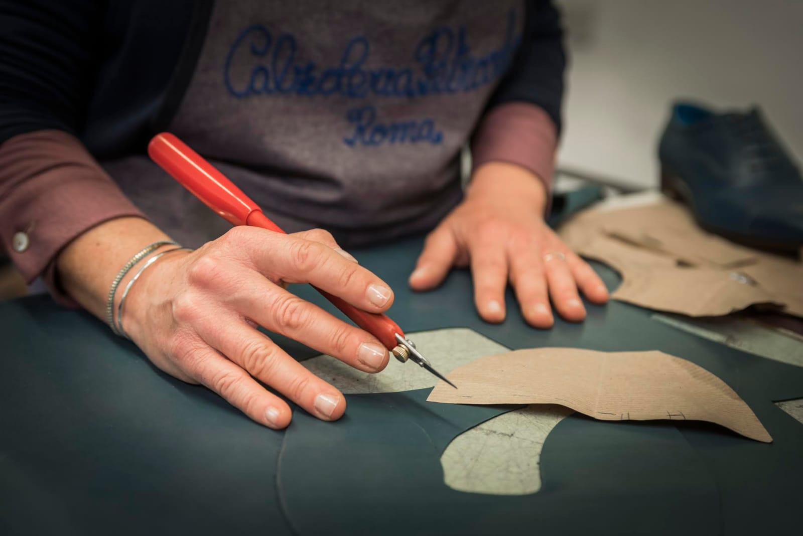 Cutting leather to a paper pattern at the bench